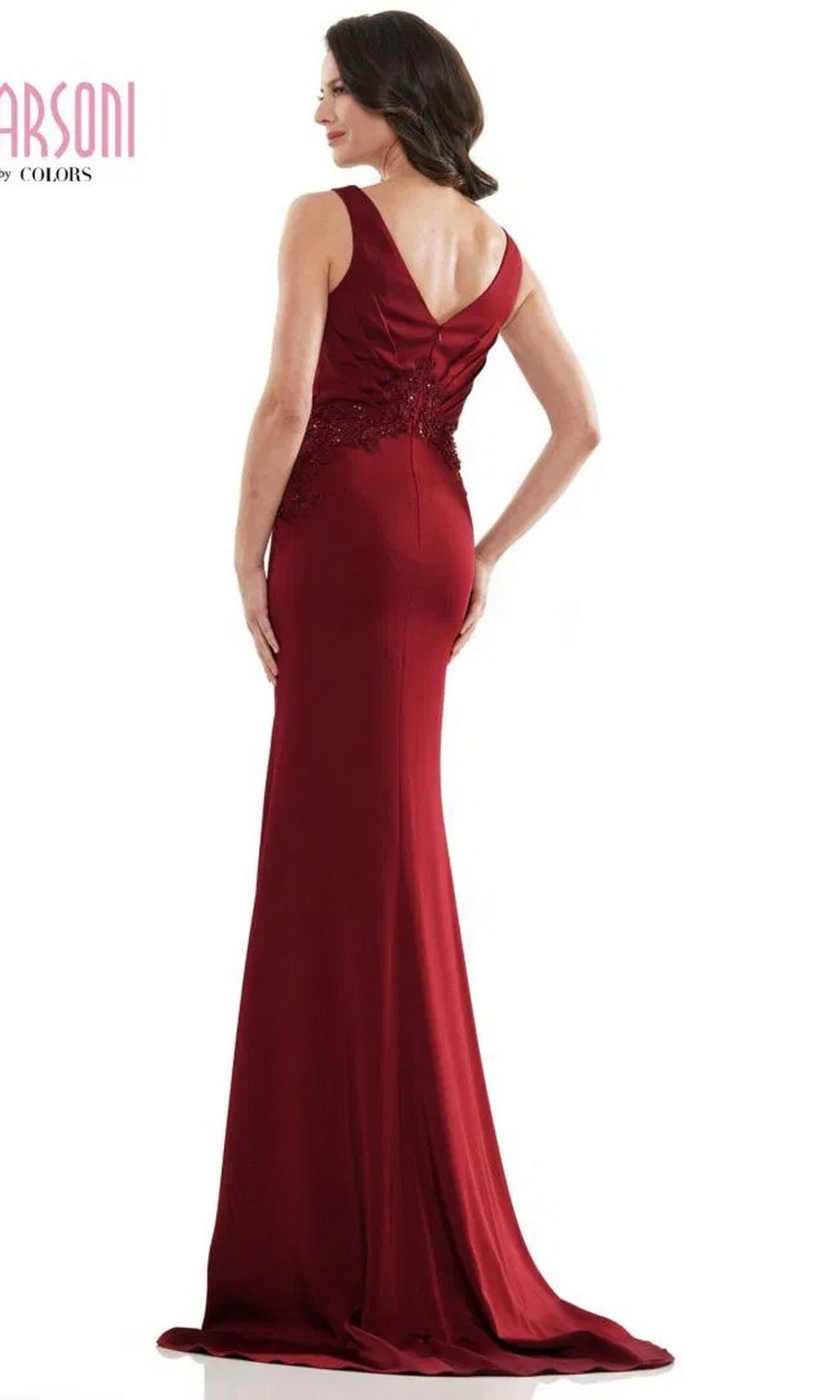 A woman wearing the Marsoni MV1054 Long Formal Dress—a sleeveless, floor-length deep red gown with an embroidered bodice and V-shaped back—stands facing away from the camera.